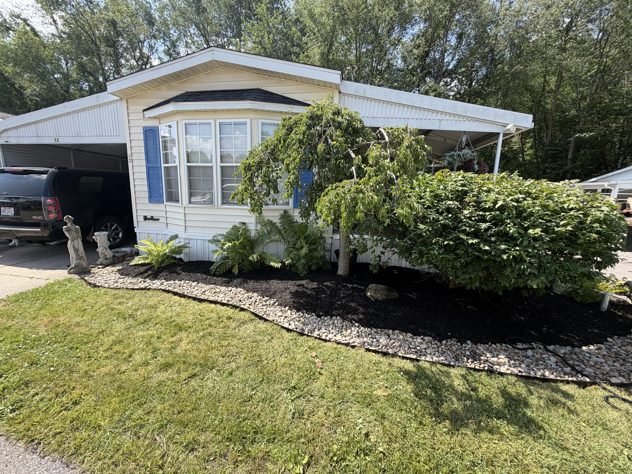 Fresh black mulch and river-rock edging around the front beds