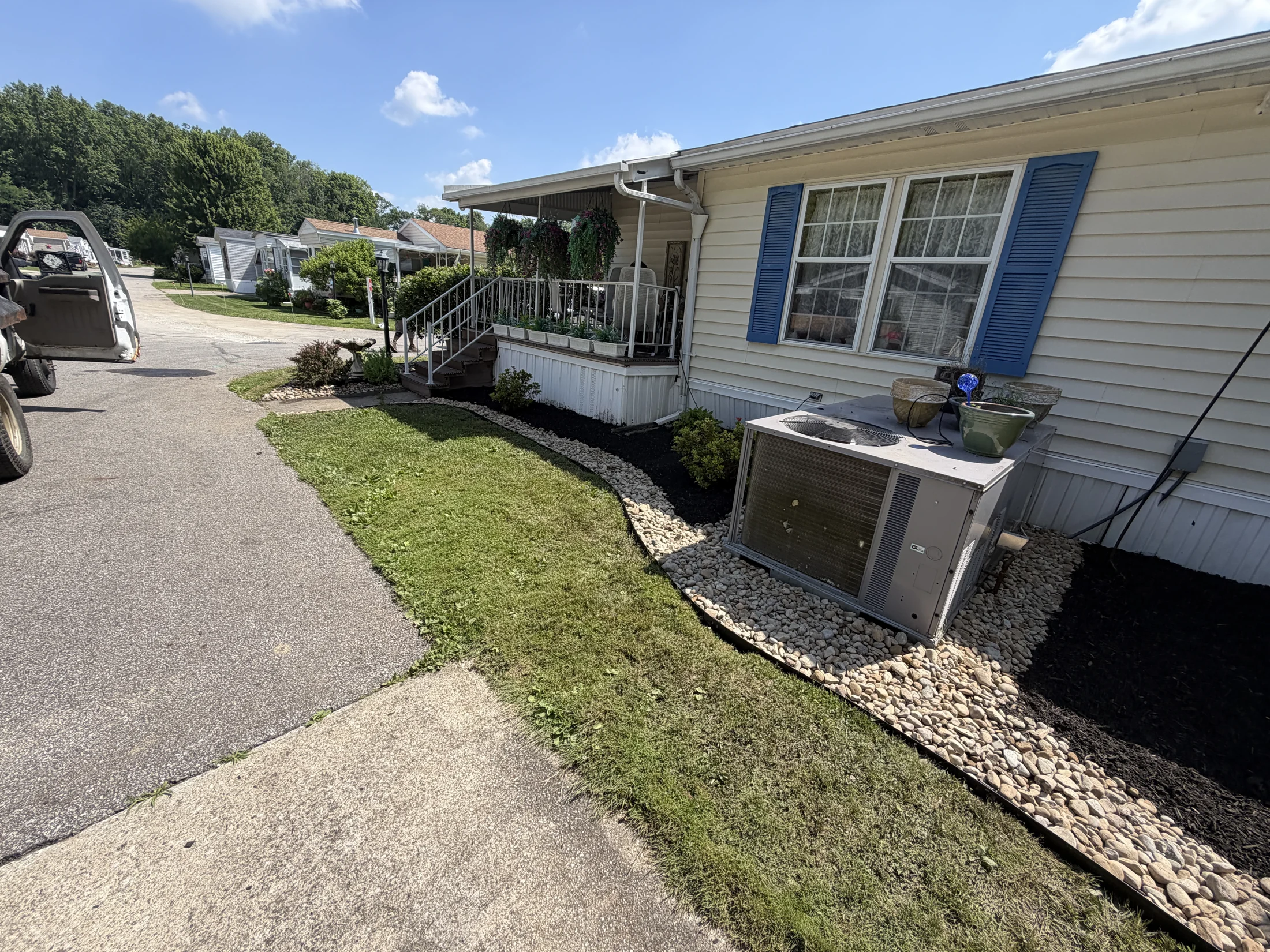 Curved mulch and river-rock beds along the side of a home