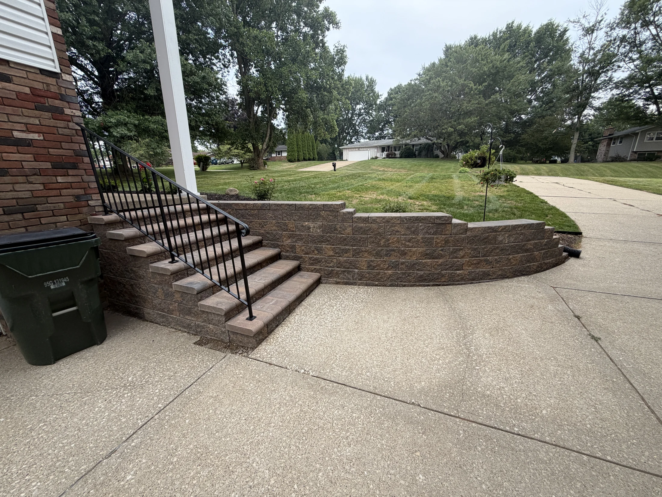 Finished stone steps, black railing, and curved retaining wall